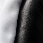 Macro close-up of white cotton shirt fabric meeting the grained black leather of the Chelsea boot, detail held in both extremes