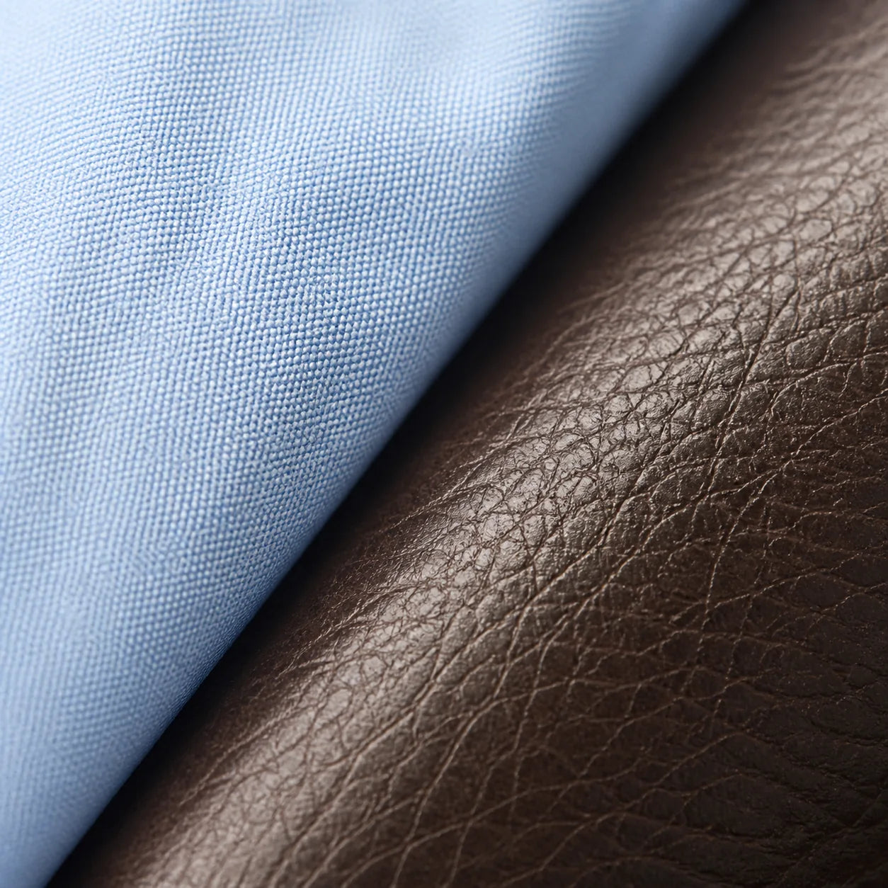 Macro close-up of light blue oxford cotton weave meeting the grained dark brown leather of the Chelsea boot