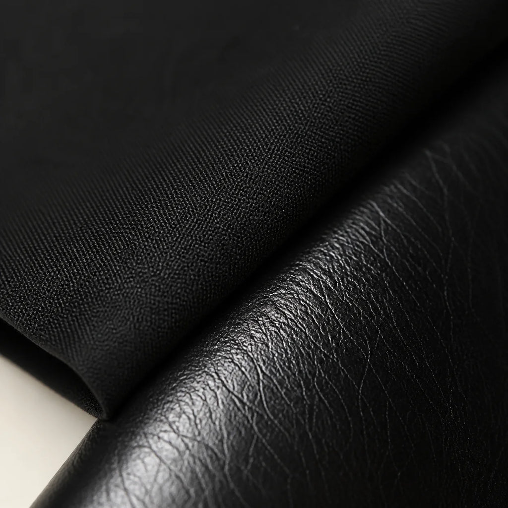 Macro close-up of matte black cotton shirt fabric meeting the grained black leather of the Chelsea boot