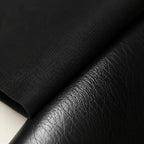 Macro close-up of matte black cotton shirt fabric meeting the grained black leather of the Chelsea boot
