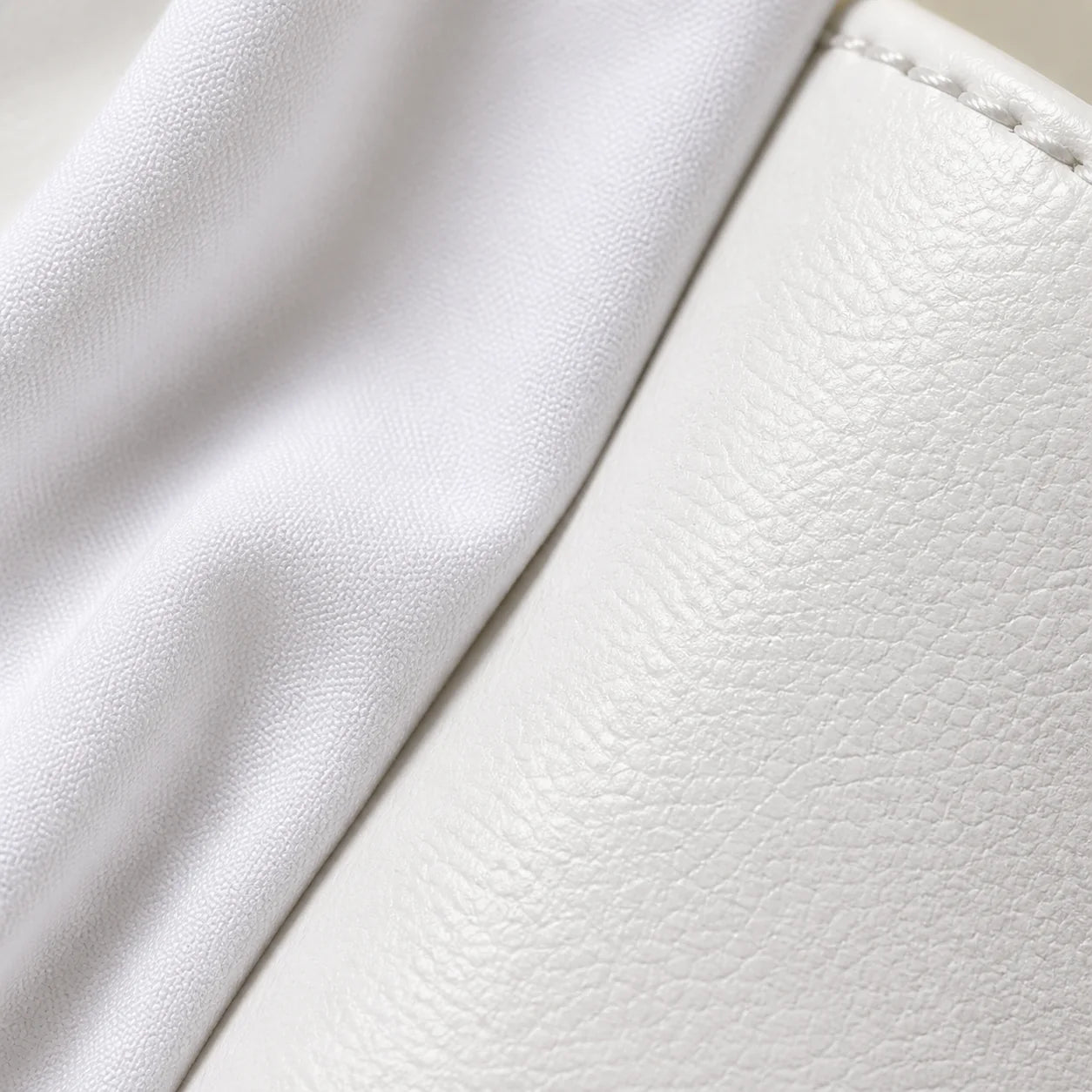 Macro close-up of white cotton shirt fabric meeting the smooth white leather of the sneaker, showing two different whites