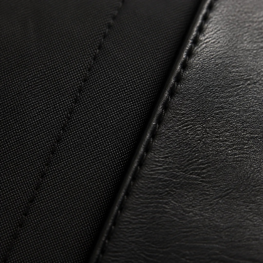 Macro close-up of matte black cotton shirt fabric meeting the stitched black leather of the Chelsea boot