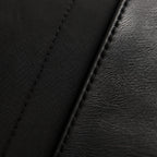 Macro close-up of matte black cotton shirt fabric meeting the stitched black leather of the Chelsea boot