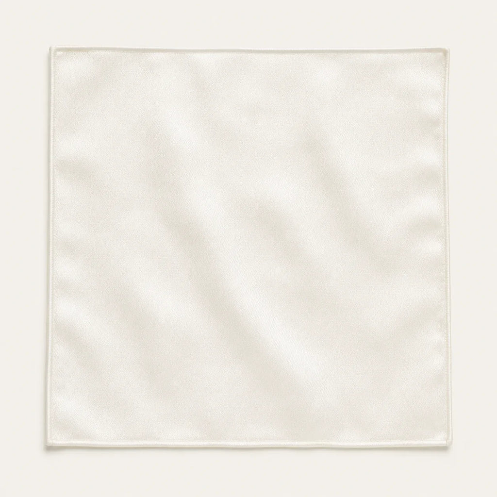 Solid ivory silk pocket square laid flat and open on a bone background, showing the full 34 by 34 centimetre square