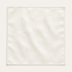Solid ivory silk pocket square laid flat and open on a bone background, showing the full 34 by 34 centimetre square