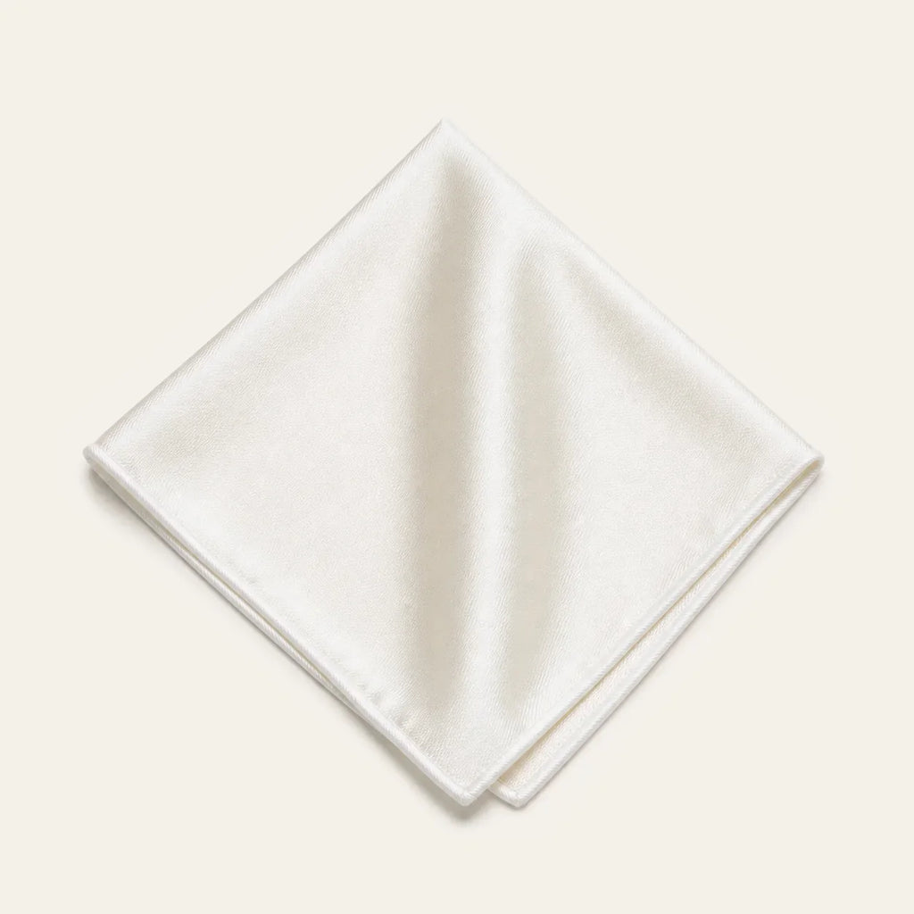 The Square in Ivory: folded silk pocket square with no contrast edge, on a bone background
