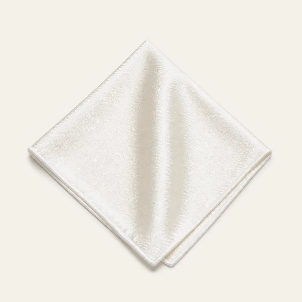 The Square in Ivory: folded silk pocket square with no contrast edge, on a bone background